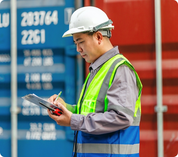 Worker in safety gear inspecting containers.