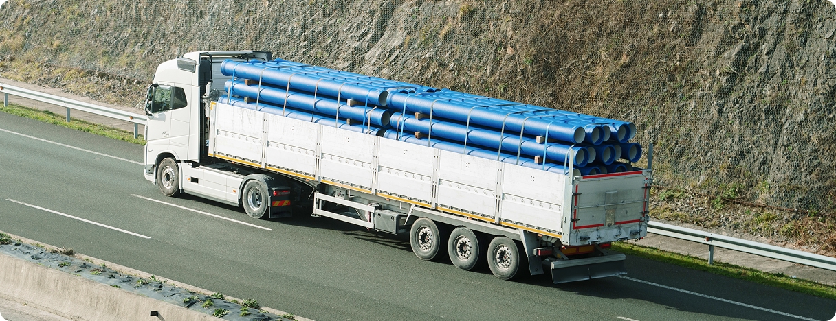 Truck transporting blue pipes on highway